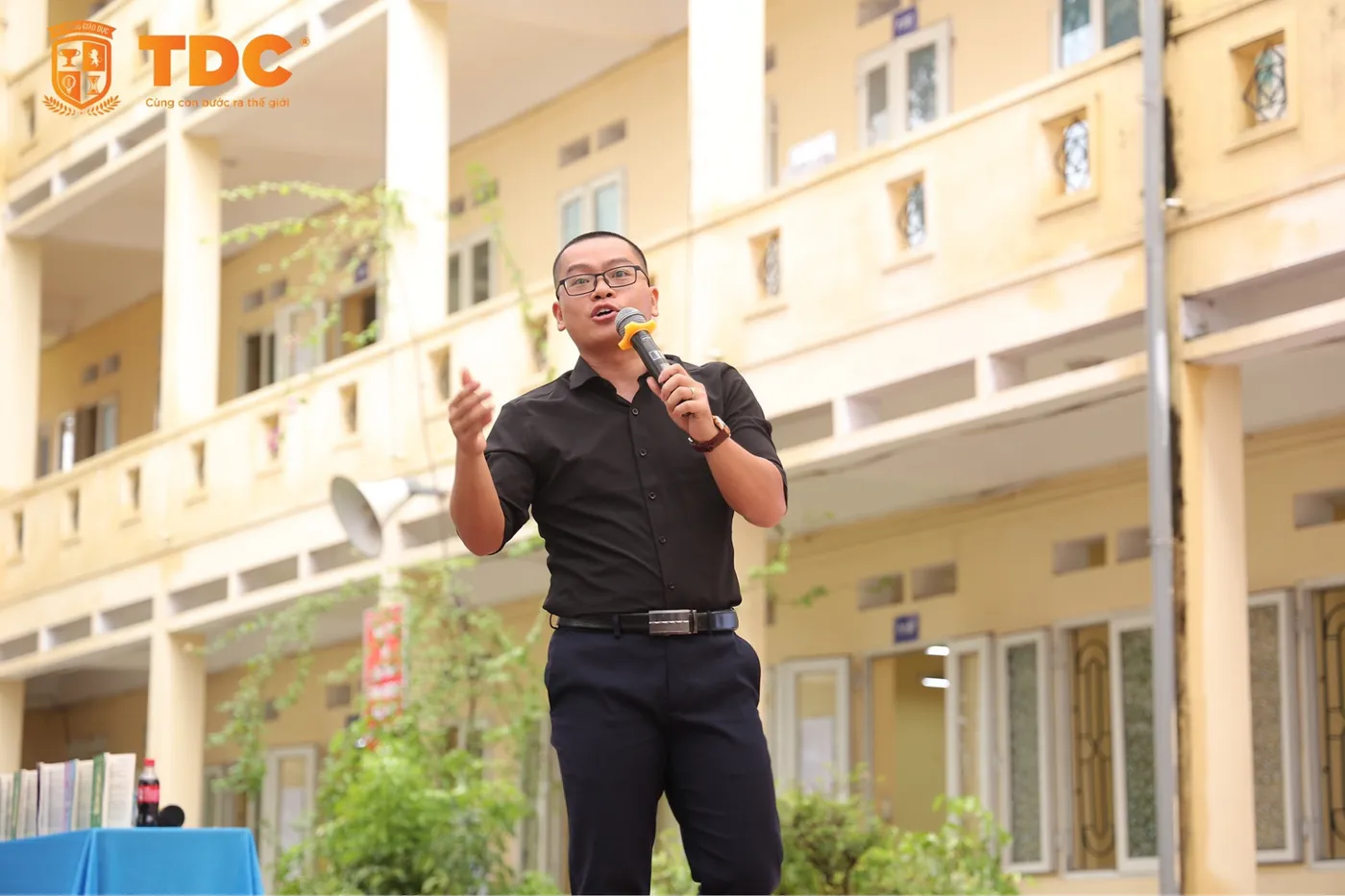 Thầy Thành cầm micro chia sẻ trong sân trường